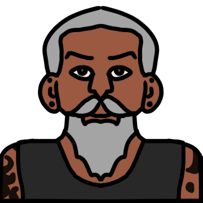 a head and shoulders portrait of a person with warm brown skin, grey straight long beard and short hair, and two black stud earrings in each ear, one in the earlobe and one higher. They are wearing a dark grey singlet and have abstract black tattoos on their arms and shoulders.